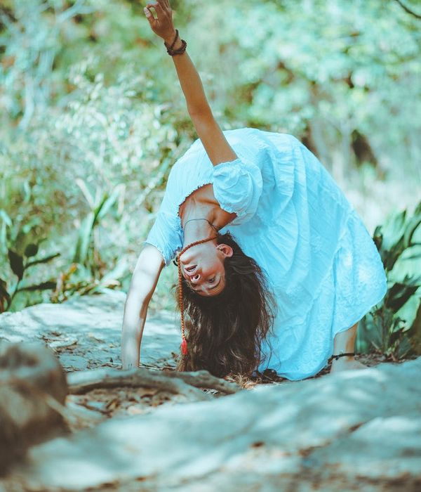 Woman in a graceful yoga pose with a serene forest background.